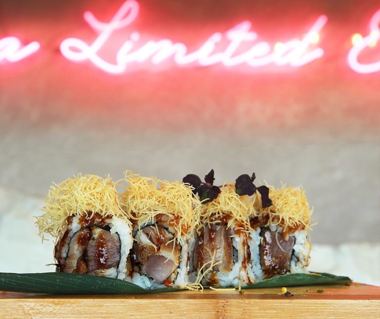 Uramaki serviti sotto una scritta al neon, a cena